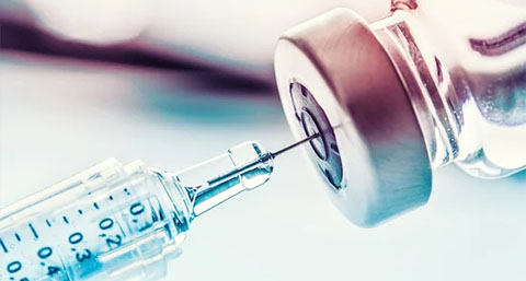 a closeup of a syringe extracting a liquid drug out of a bottle in preparation for an injection