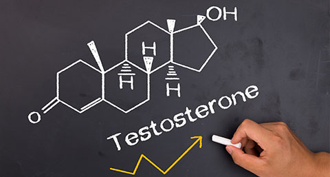 a person drawing the word testosterone and the chemical makeup of the hormone on a blackboard