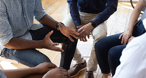 a group of people sitting together in discussion at a therapy session