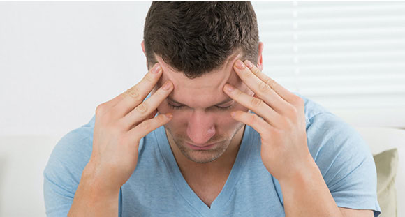 a man holding his head in pain from a migraine