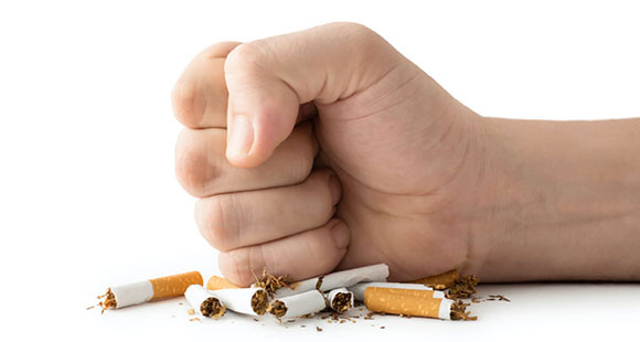 a fist coming down on half a dozen cigarettes on a white background