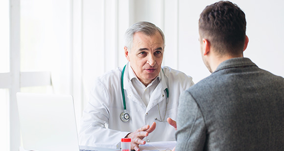 a senior doctor talking with a male patient in a doctor's office