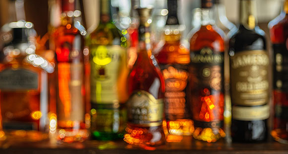 a row of bottles of alcohol behind a bar