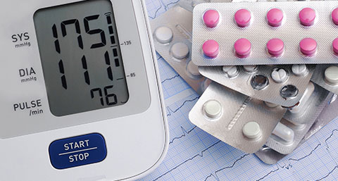 a blood pressure monitor next to blister packs of medication