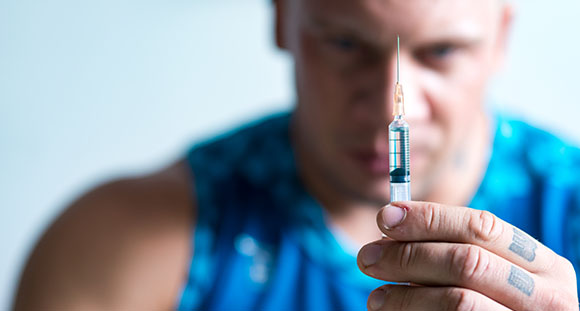 a man holding a syringe full of a steroid