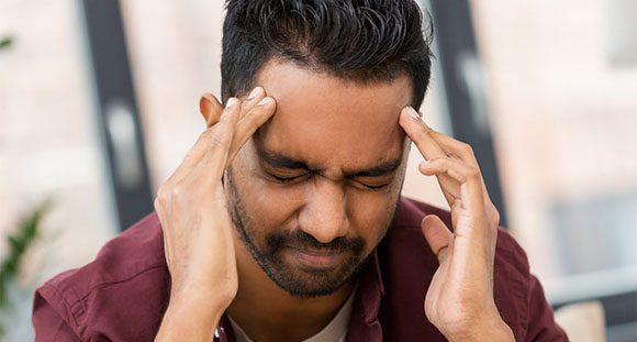 a man holding his head in pain from a migraine