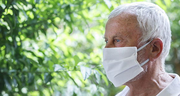 an older man wearing a white face mask outside