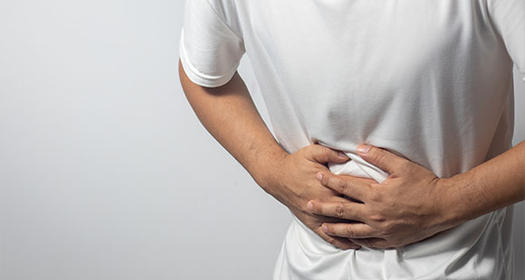 a man in a white shirt holding his stomach in pain