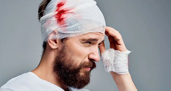 a man in pain with a bloodied head bandage 