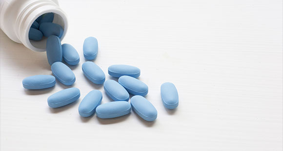 a bottle spilling 'blue pills' that are used as a temporary relief for erectile dysfunction