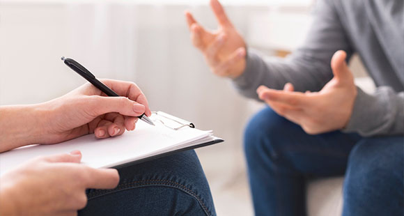 a person with a clipboard writing notes in a discussion with a patient