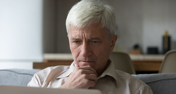 a grey haired man researching EMTT on his laptop