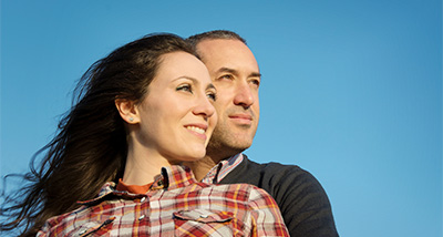 a man and a woman standing together against a blue sky