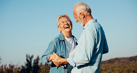 an elderly couple smiling happy outside