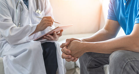 a doctor sitting down next a patient and writing notes about his worries regarding prostate cancer