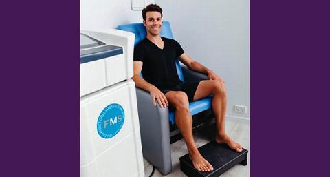 a smiling man receiving a FMS treatment through sitting on a Tesla chair